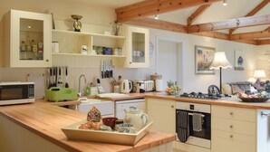 Una cocina con vigas de madera, microondas, tostadora y pileta.