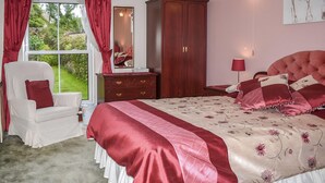 Una camera da letto con un letto grande, un armadio, una sedia e una finestra con tende.
