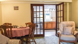 Zona pranzo con tavolo imbandito per quattro persone, una sedia in legno e una poltrona imbottita.