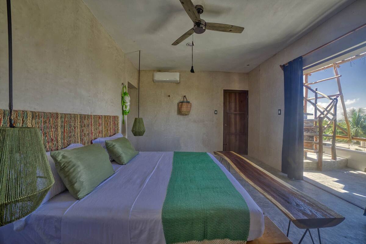 A bedroom with a bed, a ceiling fan, a window, and a view of the outside.