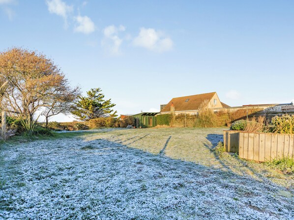 A residential property with a fenced yard, a wooden deck, and a house with a sloped roof.