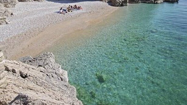 A rocky beach with clear water and a few people sunbathing. - Apartments Barbara With Swimming Pool (Moscenicka Draga)