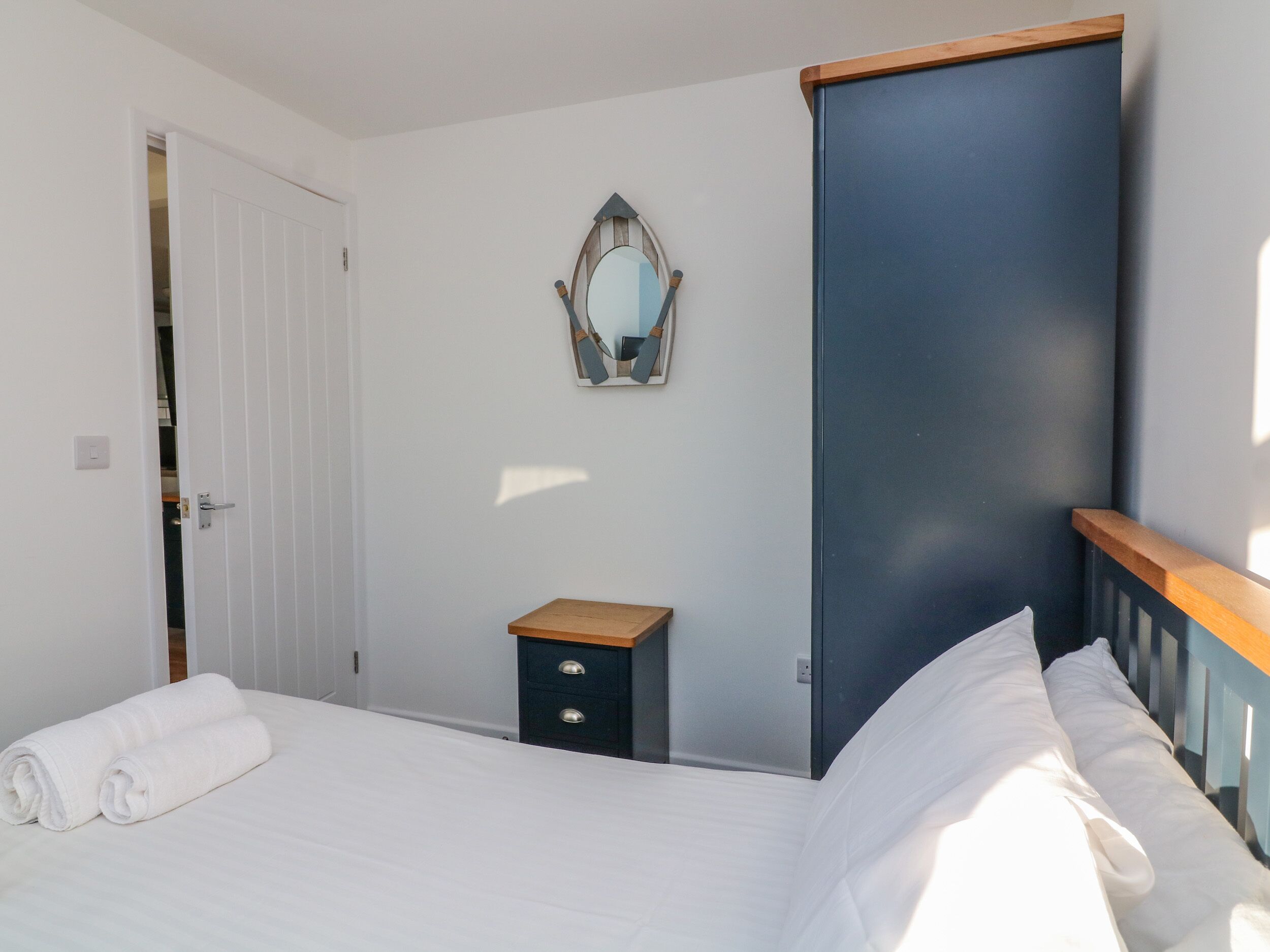 A bedroom with a bed, a dresser, a mirror, and a door.
