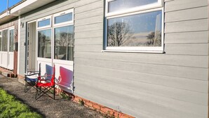 Un edificio residencial con varias ventanas, una antena visible y una pequeña zona exterior con sillas.