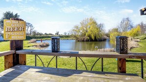 Une terrasse en bois avec une pancarte sur laquelle on peut lire : « BUVEZ DE LA BONNE BIÈRE AVEC DE BONS AMIS », et un panneau d’avertissement à proximité.