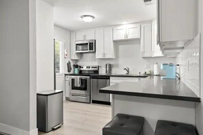A modern kitchen with white cabinets, stainless steel appliances, and a black countertop.