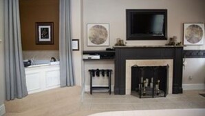A living room with a fireplace, a television mounted above it, and two framed artworks on the wall.