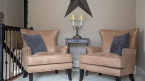 Una habitación con dos sillones color beige, un adorno con forma de estrella en la pared y una mesita con dos lámparas.