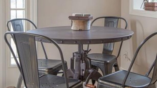 Un comedor con una mesa redonda y cuatro sillas de metal. Una decoración con forma de estrella grande cuelga de la pared sobre la mesa.