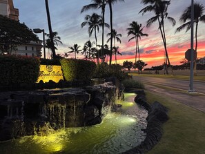 A landscaped area with a waterfall, palm trees, and a sign for 'Brando Villas.'
