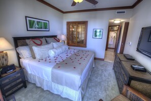 Un dormitorio con cama, mesitas de noche, televisor, ventana con persianas y puerta que da a un armario.