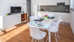 A modern kitchen with white cabinets, a built-in oven, and a stainless steel range hood. - Residenza Torre Bianca (Lignano)