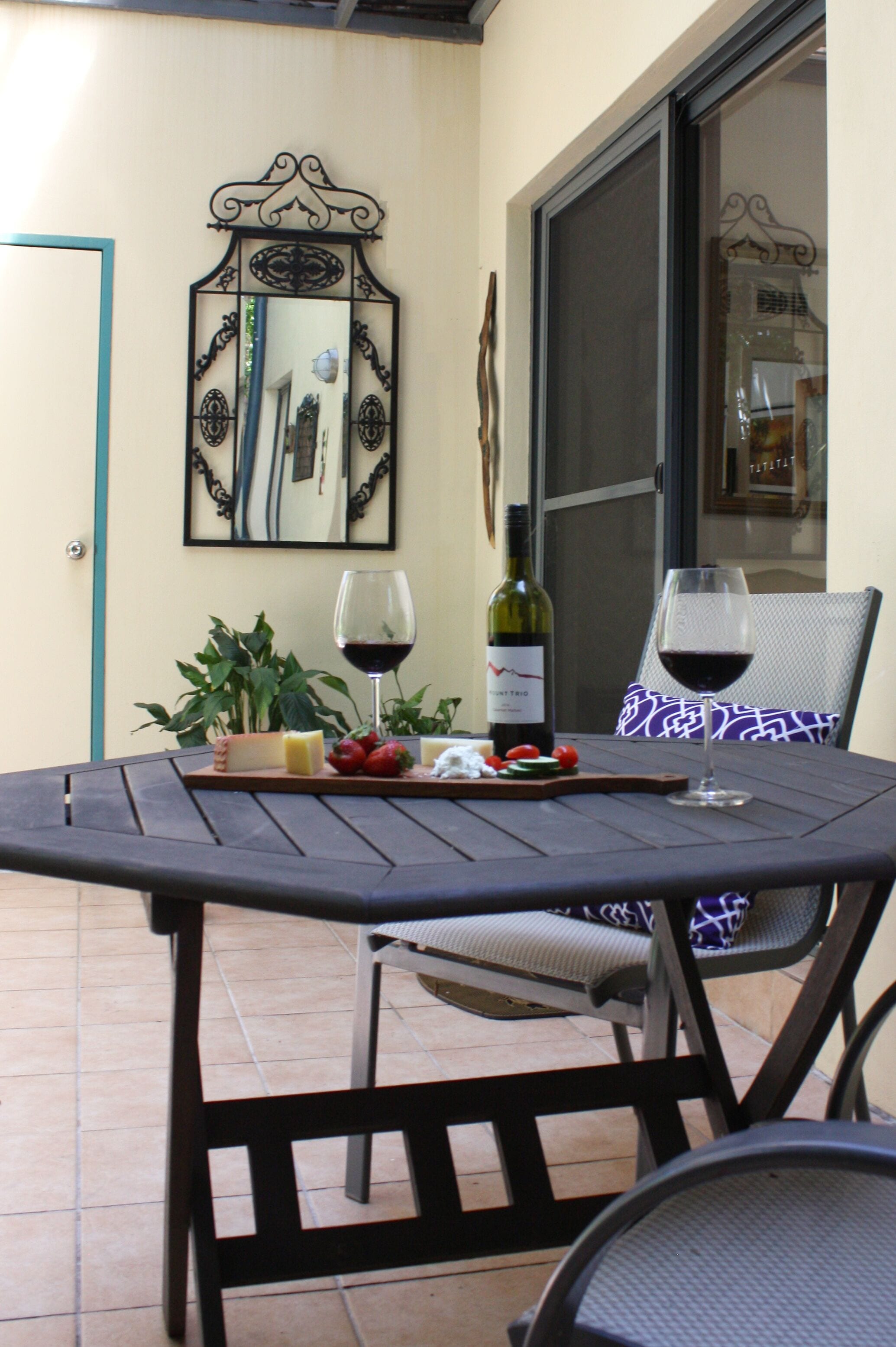 Une table à manger avec une bouteille de vin, des verres et une assiette de nourriture.