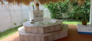 Relax in a hot tub surrounded by a tranquil outdoor setting with a potted plant nearby.