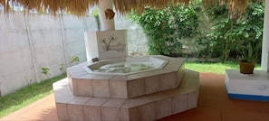 Relax in a hot tub surrounded by a tranquil outdoor setting with a potted plant nearby.