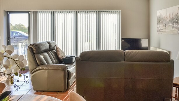 A living room with a sofa, a dining table with chairs, a TV, and a window with blinds. - 1 bedroom accommodation in Doddington, near Lincoln (Doddington, near Lincoln)
