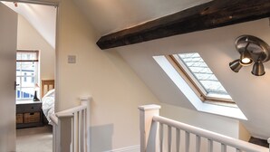 A room with a sloped ceiling, a skylight, a white railing, and a window with blinds. - 3 bedroom accommodation in Swanage (Swanage)