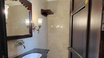 Un baño con pared de mármol, un lavabo con espejo, un perchero y una puerta.
