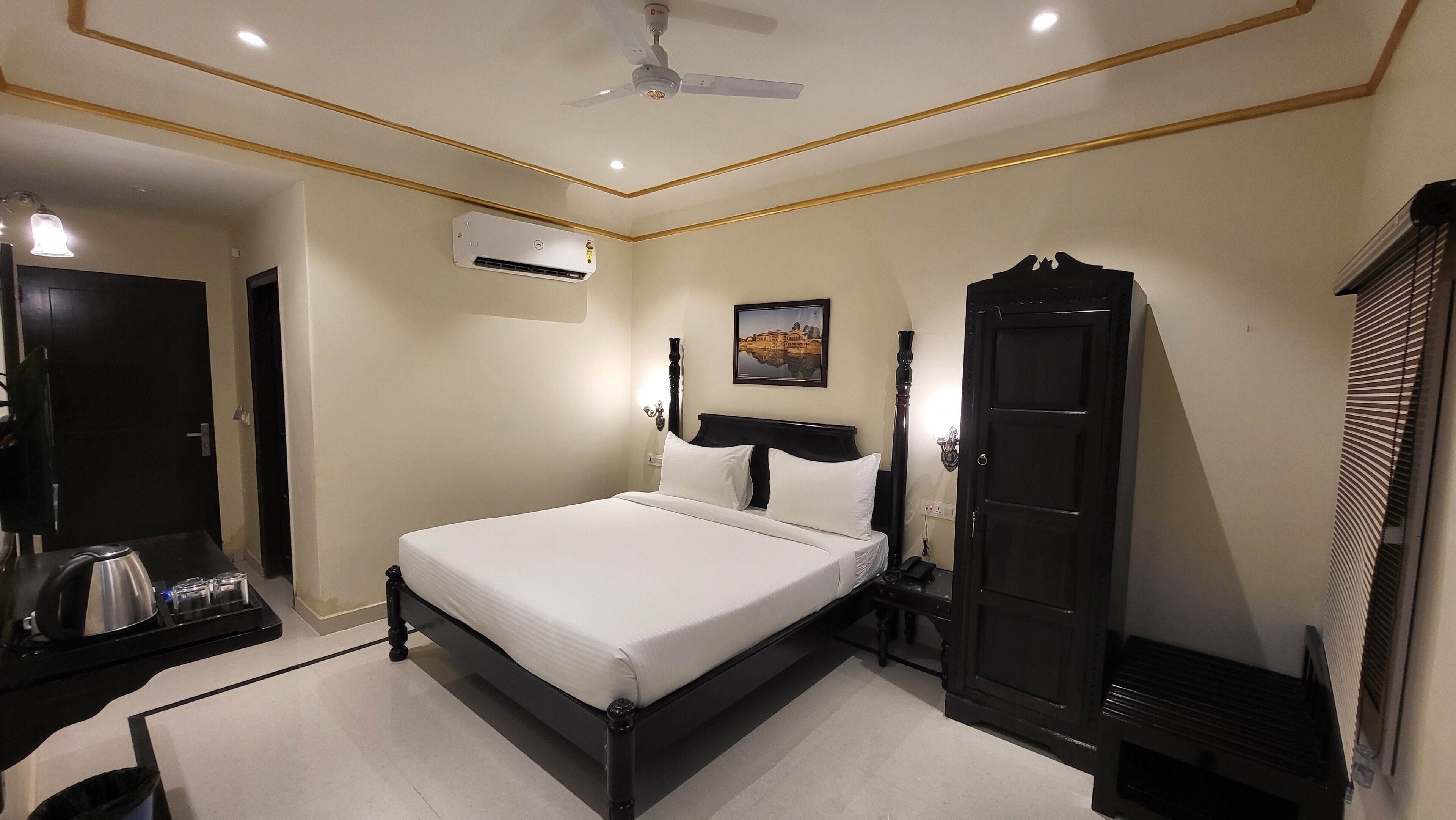 Un dormitorio con cama, armario, equipo de aire acondicionado, ventilador de techo y un cuadro en la pared.