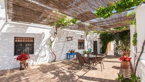 A patio with a table and chairs, surrounded by white walls and covered by a woven shade. - La Casa de Aulabar Belmez de la Moraleda by Ruralidays (Jaén)