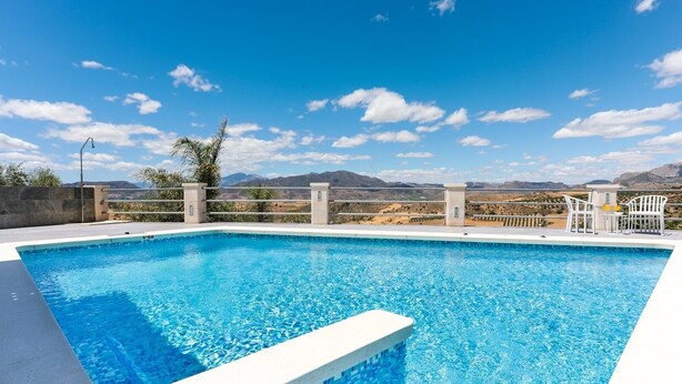 A rectangular swimming pool with clear blue water, surrounded by a concrete deck and a metal railing. - Villa Rural el Mirador Álora by Ruralidays (Málaga)