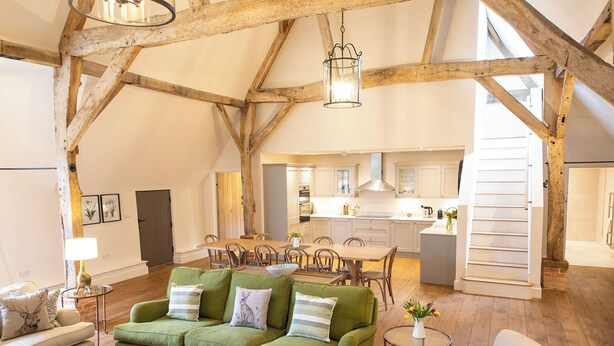 A spacious loft with exposed wooden beams, a dining area, and a kitchen. - Olivers Barn - UK42081 (Shefford Woodlands Near Hungerford)