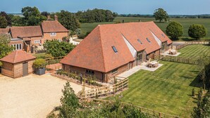 A large house with a red-tiled roof, multiple windows, and a fenced yard. - Olivers Barn - UK42081 (Shefford Woodlands Near Hungerford)