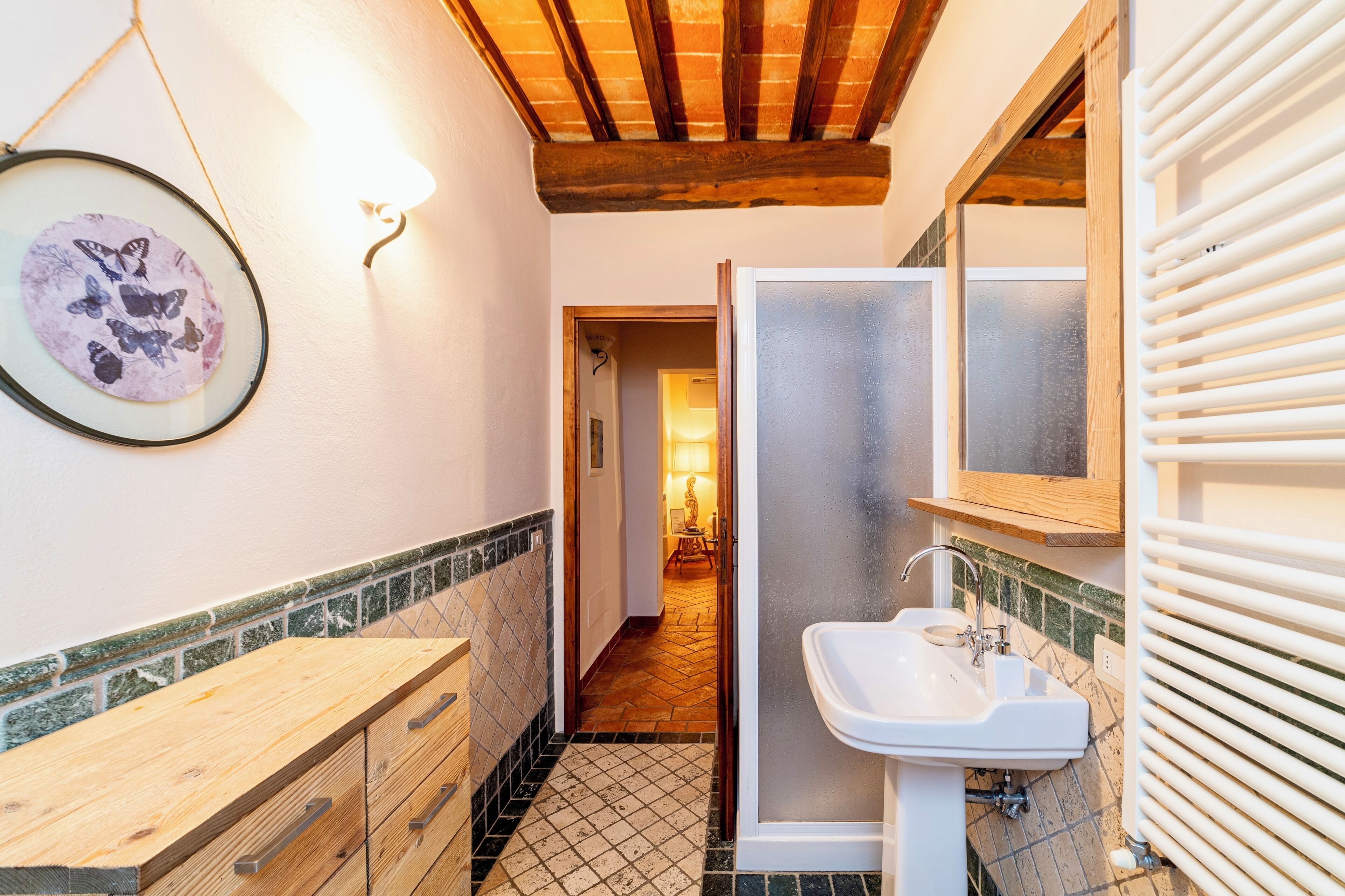 Un baño con tocador de madera, lavamanos y espejo.