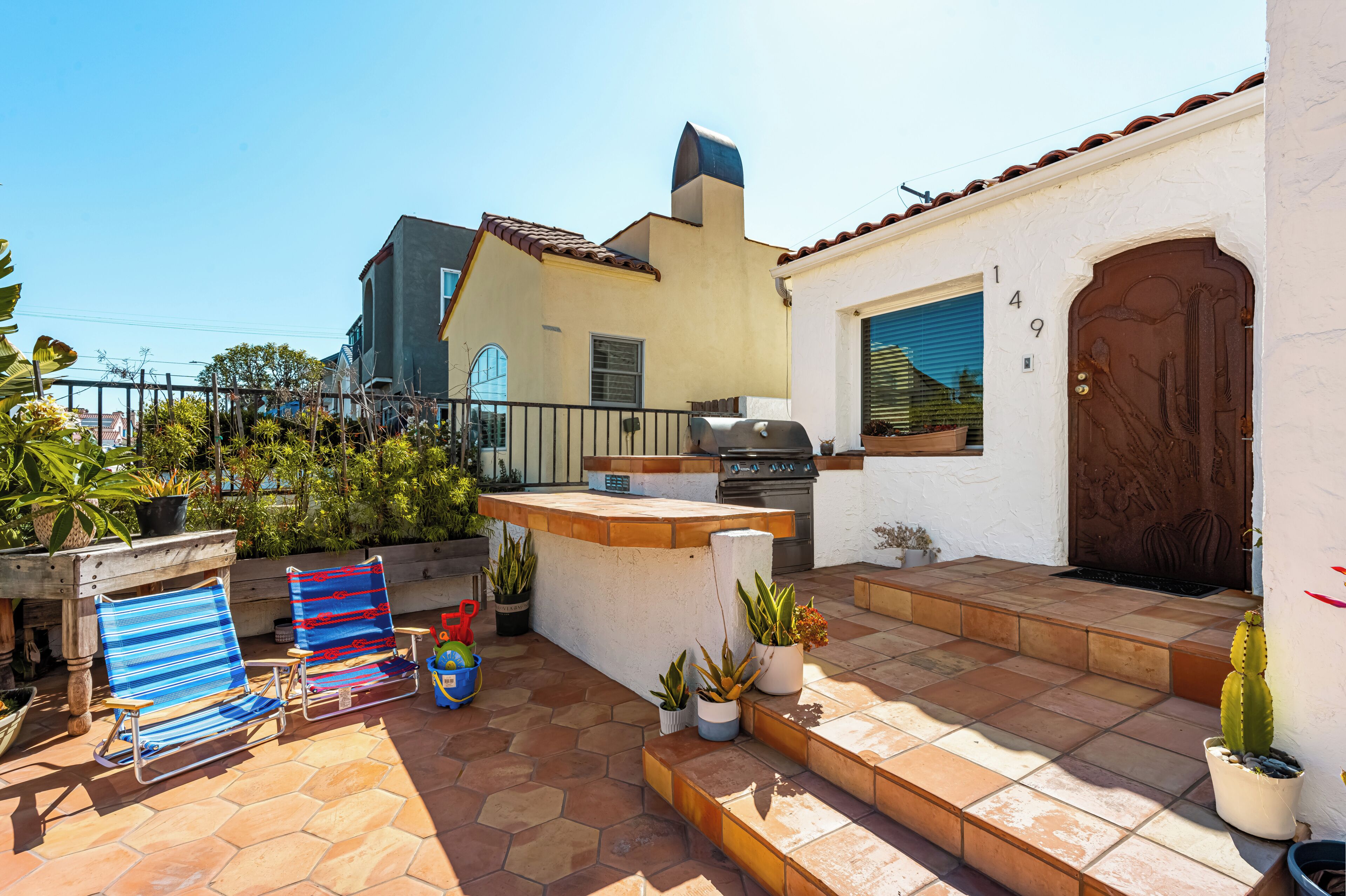 Una terrazza con barbecue, sedute all'aperto e piante in vaso.
