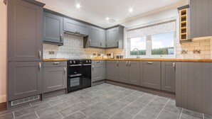 Una cocina moderna con armarios grises, un horno negro y una ventana con vistas al exterior.