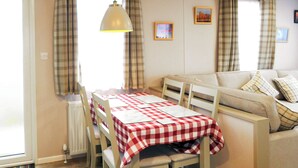 Un coin repas avec une table dressée pour deux personnes, un canapé et un radiateur.
