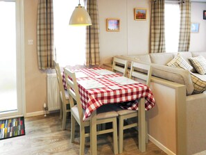 Un coin repas avec une table dressée pour deux personnes, un canapé et un radiateur.