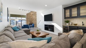 A modern living room with a sectional sofa, a coffee table, and a TV mounted on the wall. - Spacious, Updated Mountain Home with Views, Private Hot Tub and Sauna. (Fraser)
