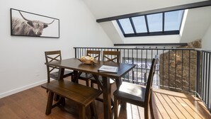 A dining area with a wooden table and chairs, a black and white photograph on the wall, and a view of a rocky landscape through a window. - Spacious, Updated Mountain Home with Views, Private Hot Tub and Sauna. (Fraser)