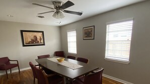 A dining room with a dark wooden table, six red chairs, a ceiling fan, and two windows with blinds. - Comfortable home in the heart of Conroe, Texas and minutes away from Lake Conroe (Conroe)