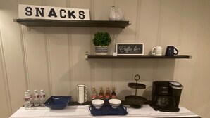 A snack station with a sign labeled "SNACKS," a coffee bar sign, and various beverages and containers on a table. - Comfortable home in the heart of Conroe, Texas and minutes away from Lake Conroe (Conroe)