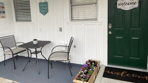 A front porch with a green door, a welcome sign, a small table with chairs, and a flower planter. - Comfortable home in the heart of Conroe, Texas and minutes away from Lake Conroe (Conroe)