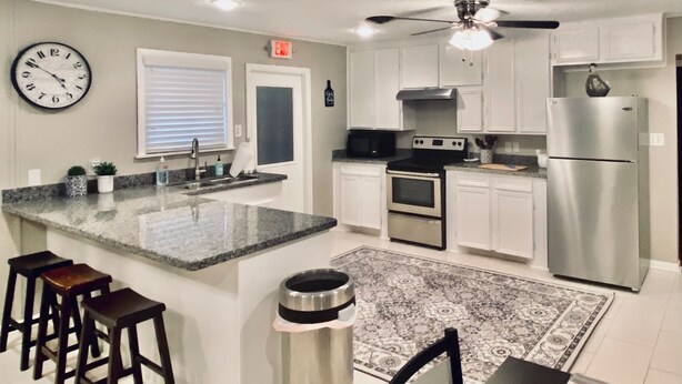 A modern kitchen with a central island, stainless steel appliances, and a ceiling fan. - Comfortable home in the heart of Conroe, Texas and minutes away from Lake Conroe (Conroe)