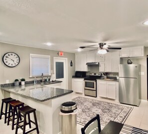 A modern kitchen with a central island, stainless steel appliances, and a ceiling fan. - Comfortable home in the heart of Conroe, Texas and minutes away from Lake Conroe (Conroe)