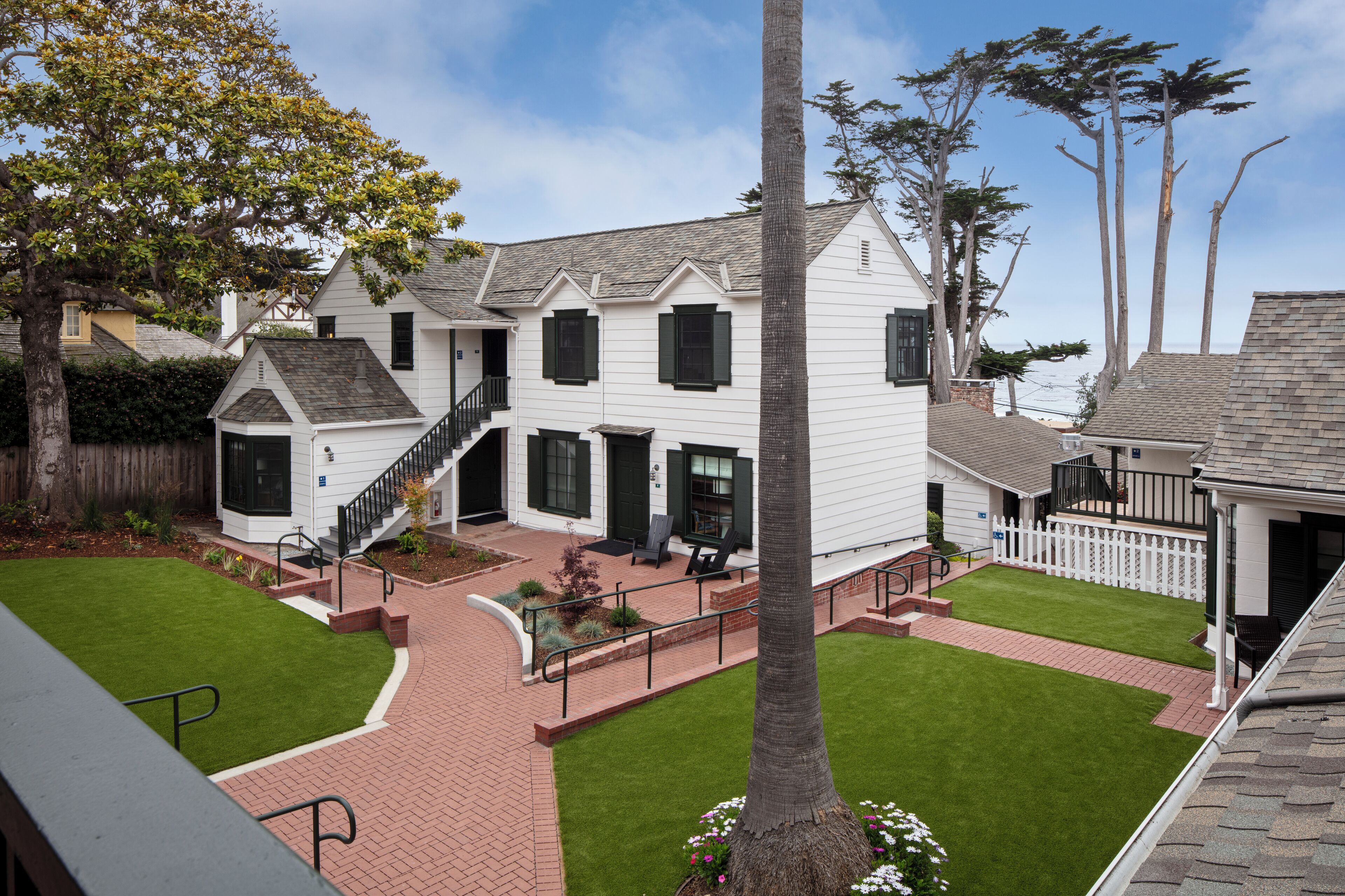 A two-story house with a front porch, a staircase, and a small garden area.