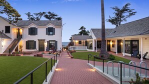 A residential area with a well-maintained lawn, a brick pathway, and houses with visible windows and doors. - Carmel Beach Hotel (Carmel)