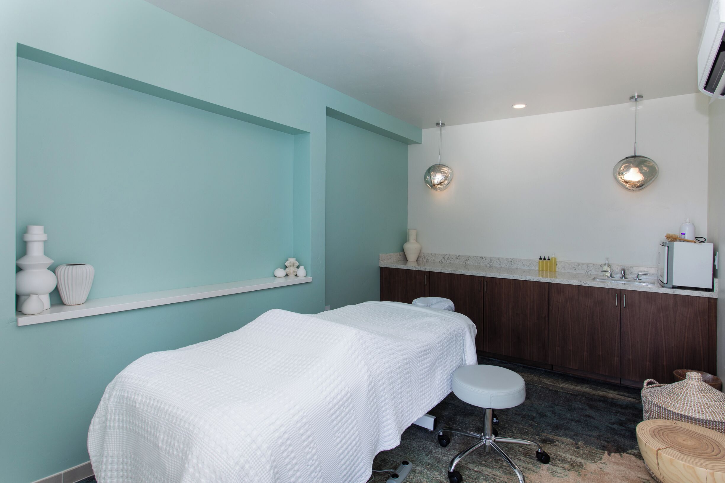 A spa room with two beds, a sink, and a vanity.