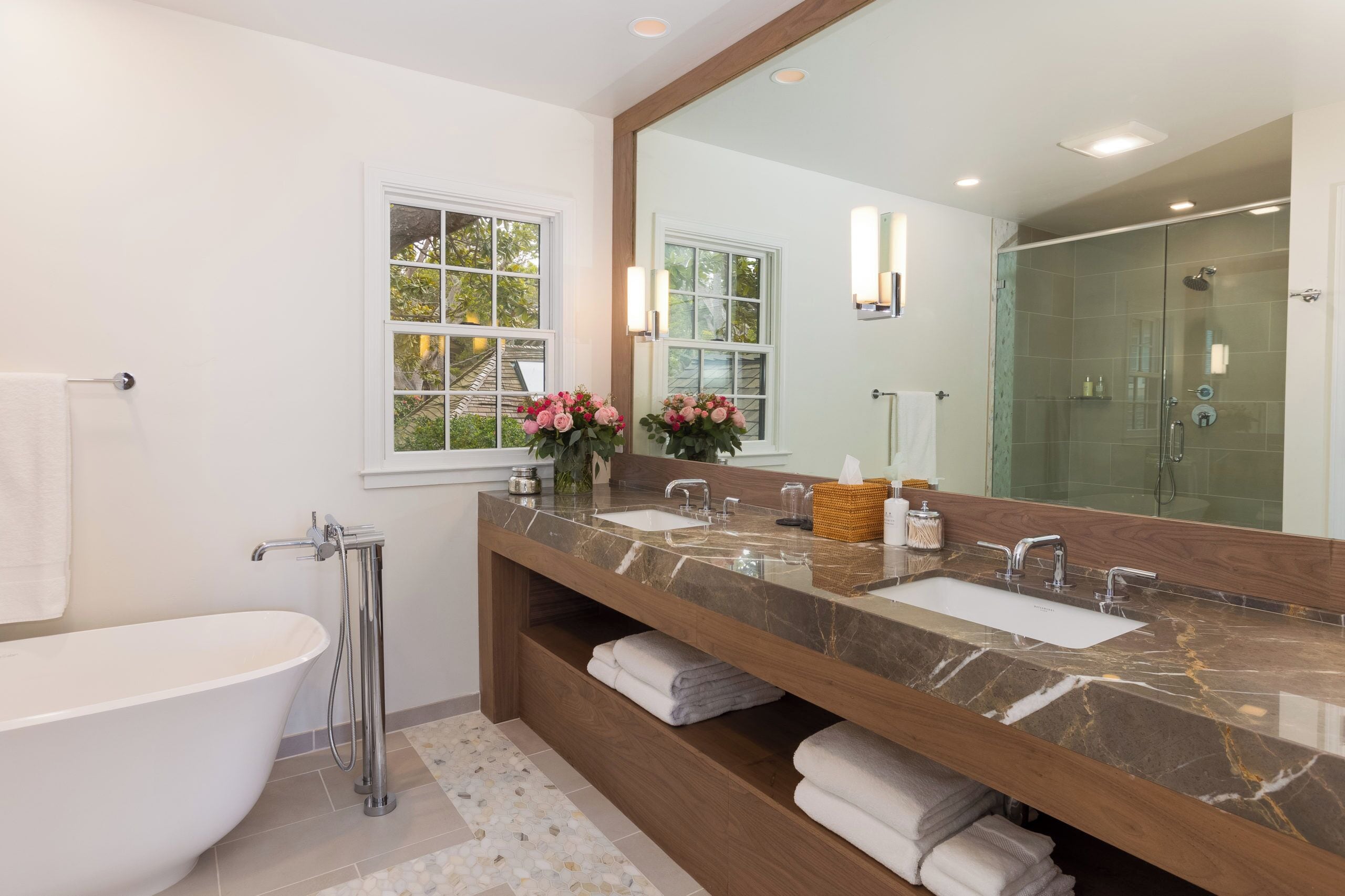 A modern bathroom with a freestanding bathtub, a large vanity with two sinks, and a walk-in shower.