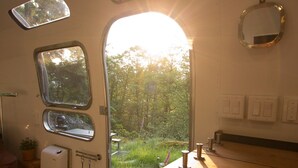 A compact kitchen with a wooden countertop, a sink, and a window overlooking a forest. - Wildernest Mountainside Airstream Getaway (Bowen Island)