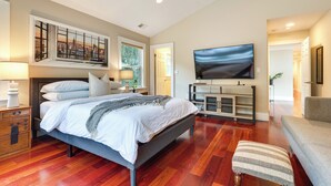 Un dormitorio moderno con una cama grande, un televisor de pantalla plana y una obra de arte urbana en la pared.