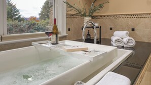 Un baño moderno con bañera, una botella de vino y un perchero.