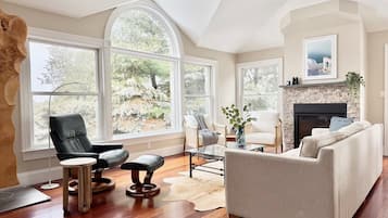 Amplia sala de estar con chimenea, ventanas grandes y un rincón de estar acogedor.