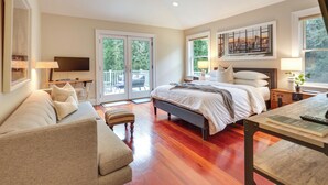 Un dormitorio espacioso con una cama grande, un sofá, un escritorio con lámpara y un televisor.