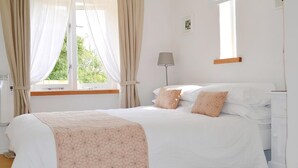 A bedroom with a bed, curtains, a lamp, and a window. - 2 bedroom accommodation in Valast Hill, near Stackpole (Valast Hill, near Stackpole)