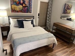 A bedroom with a bed, bedside tables, a dresser, and two paintings on the wall.
